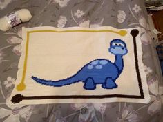 a crocheted blanket with a blue dinosaur on it