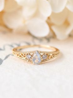 a close up of a gold ring with a white flower in the background and a bouquet of flowers behind it