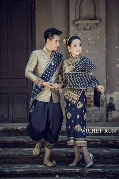 a man and woman dressed in traditional thai garb standing on the steps with their arms around each other