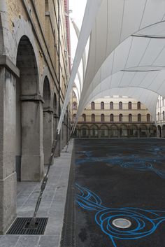 an empty parking lot with blue graffiti on the ground and buildings in the backround