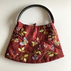 "This is an adorable embroidered purse with beautiful spring flowers and butterflies. This fabric handbag is made of beautiful burgundy taffeta fabric and plastic floral engraved handle. The interior is lined in synthetic fabric. There is one compartment and one pocket with zip closure. There is a fabric label inside which reads \"Handmade Product from Vietnam\" Era: 90s Condition: There is a small stain about two inches under the top stitch of the purse on the front, which I have tried to captu Handheld Embroidered Bags For Everyday Use, Traditional Handmade Bag For Spring, Red Handheld Bags For Spring, Red Handheld Bag For Spring, Embroidered Square Bags For Everyday Use, Embroidered Square Bag For Everyday Use, Traditional Handmade Bags For Spring, Square Embroidered Bag For Everyday Use, Embroidered Handheld Satchel For Everyday