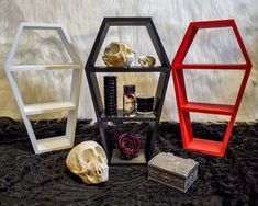 three shelves with skulls, candles and other items in them sitting on a black furnishing