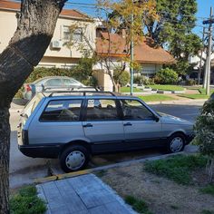 a car parked on the side of a street next to a tree