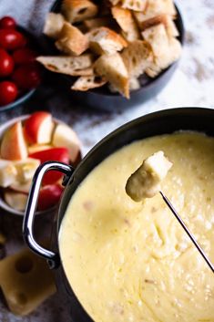 a bowl filled with dip next to bowls of crackers and fruit