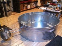 a large metal tub sitting on top of a hard wood floor next to a shelf