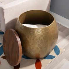 a gold vase sitting on top of a rug next to a wooden container with a lid