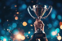 a person holding up a trophy in front of a blurry blue and green background