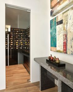 a wine cellar is shown in the entryway to this modern style home with wood flooring and white walls