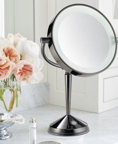 a table with a mirror and flowers on it in front of a bathroom counter top