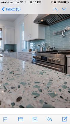 a kitchen counter top with an oven and stove in the middle, and blue glass tile backsplash