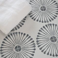 a white and black wallpaper with flower designs on the floor next to a towel