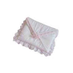 a white pillow with pink trim on the edges and a bow at the top, sitting on a white surface