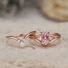 two rings with pink and white diamonds on them sitting on a stone surface next to each other