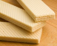 three pieces of white wafer sitting on top of a wooden table