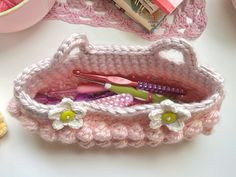 a crocheted pink purse with toothbrushes and scissors in it