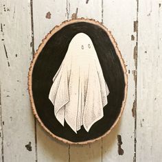 a wood slice with a ghost painted on it