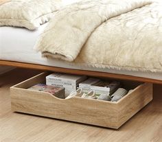 a bed with a white fur blanket on top of it next to a wooden drawer