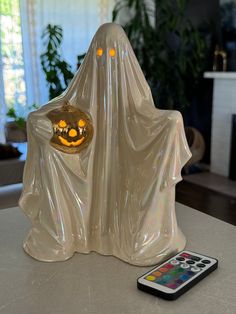 a remote control sitting on top of a table next to a ghost figurine