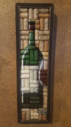 a wine bottle made out of corks in a shadow box on the wall next to a toilet