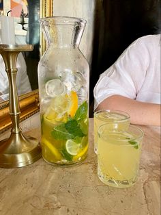 a pitcher of lemonade and two glasses on a table