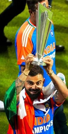 a man holding up a silver trophy on top of his head in front of other men