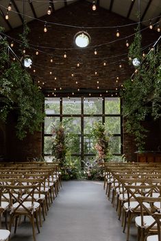 rows of wooden chairs are lined up in front of an open window with string lights hanging from the ceiling