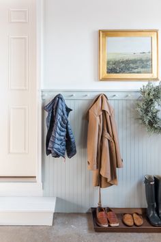 a coat rack with two coats hanging from it and shoes on the floor next to it