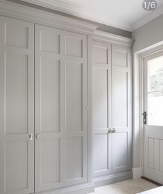 an empty room with white cupboards and drawers on the wall, in front of a window