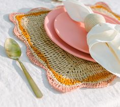 a pink plate with two white flowers on it next to a spoon and utensils