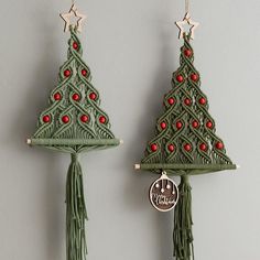 two green christmas trees hanging from hooks with red beads and tassels on them