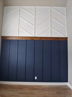 an empty room with blue painted walls and wood paneling on the wall, in front of a wooden floor