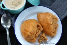 two pastries on a white plate next to a cup of coffee and spoons