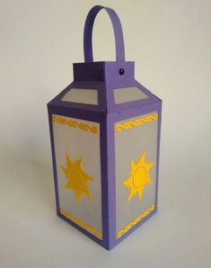 a purple lantern with yellow sun and moon on the front, sitting on a white surface