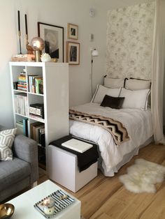 a bedroom with a bed, couch and bookshelf next to a white chair