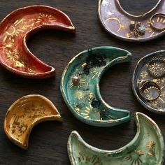 five different shaped dishes sitting on top of a wooden table with gold and silver designs