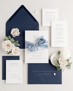 the wedding stationery is laid out on top of an envelope with flowers and ribbon