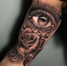 an eye with a rose tattoo on the arm is shown in black and grey colors