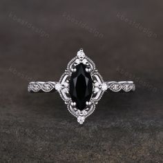 an oval black diamond engagement ring with filigrees on the sides and shoulders