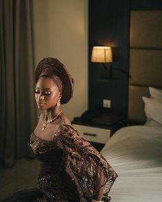 a woman sitting on top of a bed next to a night stand in a hotel room