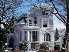 a large white house with snow on the ground and trees in front of it,