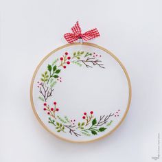 an embroidered christmas wreath with red berries and green leaves