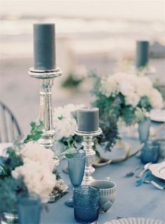 the table is set with blue and white dishes, silver candlesticks, and flowers