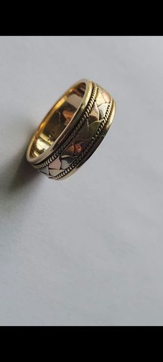 two gold wedding rings sitting next to each other on a white surface with one ring in the middle