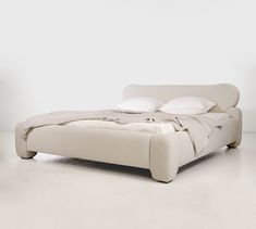 a white bed with two pillows on top of it