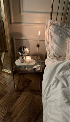 a bed with white sheets and candles on top of it next to a mirror table