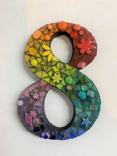 the letter s is made up of many different colored glass tiles and flowers on it