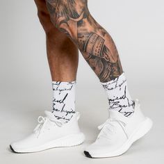 a man's legs with tattoos and white sneakers