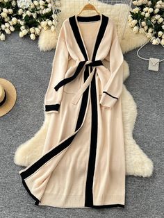 Tempt your fashion senses with this elegantly long cardigan, which combines a neutral beige hue with bold black detailing for a timeless piece. This garment's length and relaxed fit make it an ideal choice for those seeking both style and comfort. Weighing just 0.91 kg, it is light enough for all-day wear yet substantial enough to provide warmth. The cardigan's versatile design allows it to be worn open or cinched at the waist with its chic tie belt, adapting to both casual and formal settings. Elegant Beige Winter Cardigan, Elegant Beige V-neck Cardigan, Chic Beige Long Sleeve Cardigan, Long Cream Sweater Coat For Spring, Cream Open Front Sweater Coat For Spring, Chic Cream Long Sleeve Sweater Coat, Beige V-neck Sweater Coat For Spring, Elegant Beige V-neck Sweater Coat, Long Beige Cardigan For Spring