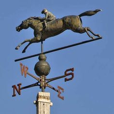 a statue of a horse and jockey on top of a weather vane