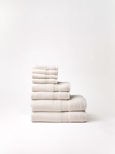 a stack of white towels sitting on top of each other in front of a white wall